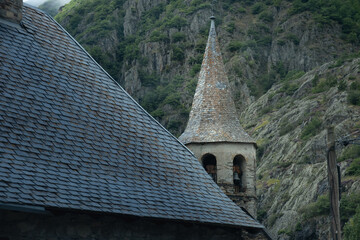 Detail of a black slate roof typical of the Pyrenees mountains with a church tower in the village of Unha, near Baqueira in Spain