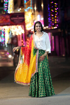 A radiant smile and colorful traditional dress light up the night cityscape. A beautiful blend of culture and modern city glow.