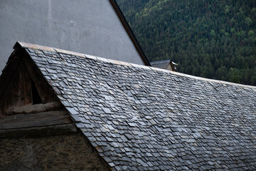 a black slate roof typical of the Baqueira region in the Pyrenees of Spain. Old stone houses prepared for the snow and cold of the area. Artisan manual construction