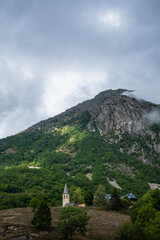 Panoramic mountain view with the Church of Santa Eulalia de Unha with the Unha peak in the background. The town is located in the Aran valley, near Baqueira. Pyrenees Mountains, Spain