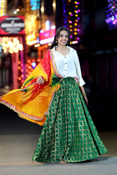 A radiant smile and colorful traditional dress light up the night cityscape. A beautiful blend of culture and modern city glow.