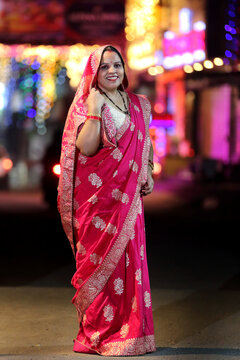 A radiant smile and colorful traditional dress light up the night cityscape. A beautiful blend of culture and modern city glow.