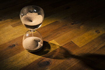 Sand flowing through the sand clock neck on a blurred gold and black background, macro shot. Time...