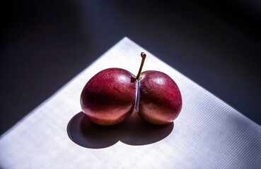 A pair of plums on a windowsill, illuminated by a ray of sunlight. It looks like a heart.