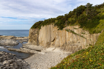 Rocks of Stolbchaty. landscape with columnar basalt lavas rocks forming a natural geometric pattern. Geographic cape on the east shore of Kunashir Island of Sakhalin Oblast, Russia. Mendeleyev volcano