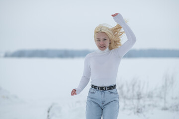 Portrait of young beautiful blonde girl outdoors in winter.