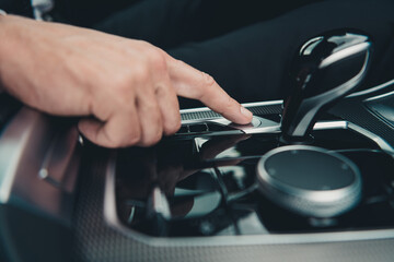 Close-up of a hand pressing a button in a car interior, showing modern technology and driving controls