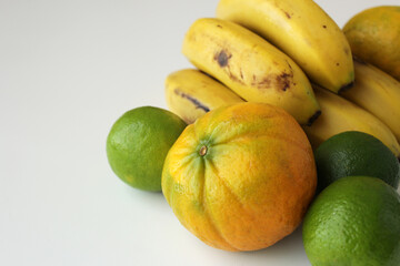 Bananas, limes and oranges on white background. Healthy fresh brazilian tropical fruits for mediterranean diet. Sustainable agriculture concept.