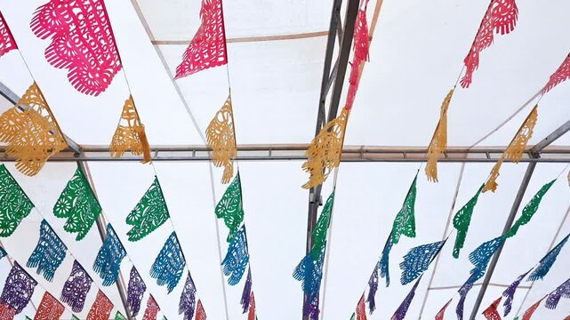 Colorful papel picado flags decorating a white tent for a festive mexican celebration