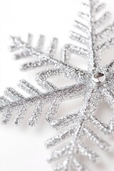 Close-up of sparkling silver snowflake on white