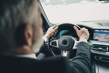Senior businessman driving in city, focusing on navigation and travel efficiency