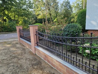 Garden fence made of forged metal iron on a sunny day