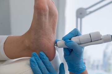 The podologist treats the feet using electric device machine. Patient on medical pedicure...