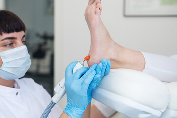 The podologist treats the feet using electric device machine. Patient on medical pedicure...