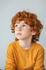Naklejka premium Thoughtful young boy with curly red hair and freckles