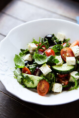 Healthy Salad with Feta Cheese, Black Olives, Cucumber and Cherry Tomatoes. Wooden background. Close up.