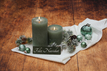 Tarjeta de felicitación navideña: Velas verdes con bolas navideñas y la inscripción Feliz...