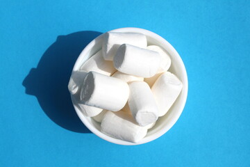 White marshmallow in a white cup is on a blue background.	