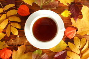 Autumn theme with cup of tea and yellow leaves.