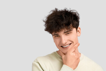 Obraz premium Smiling young man with dental braces on light background