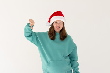Beautiful european woman wearing christmas hat looking unhappy and angry showing rejection and negative with thumbs down gesture. Bad expression.