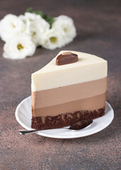 Piece of mousse cake Three chocolates on white plate