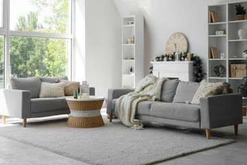 Sofas, coffee table, fireplace with Christmas decor and shelving unit in interior of living room