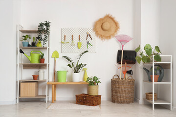 Workplace with pegboard, gardening tools and plants near white wall in barn