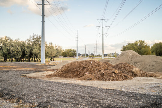 Large mulch and dirt piles at rural construction site under power lines