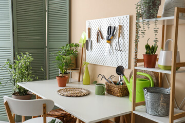 Interior of workshop with workplace, pegboard, gardening tools and plants