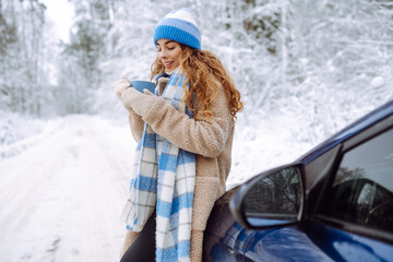 Happy woman near a car in a snowy forest. A walk through the winter forest. Concept of fun, relaxation.