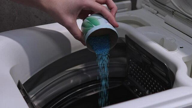 Woman pouring laundry beads into drum of top-loading washing machine, preparing for wash cycle