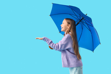 Cute teenage girl with blue umbrella on color background