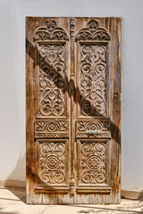 Ancient old wooden carved door, dried out and shabby. Beautiful floral pattern, Egypt