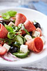 Salad with Salami, Feta Cheese, Black Olives, Cucumber and Cherry Tomatoes. Close up.