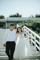 Naklejka premium A bride and groom are walking down a set of white steps
