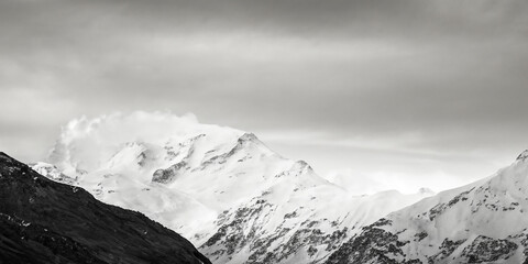 Obraz premium Majestic snow-capped mountains under dramatic sky in monochrome