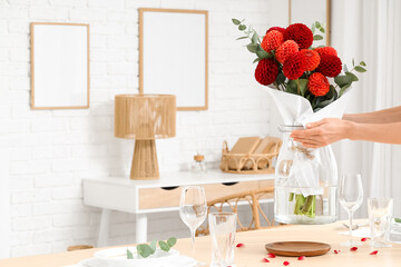 Female hands with bouquet of dahlia flowers in interior of living room