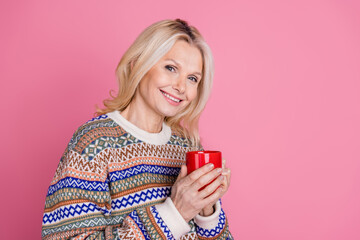 Photo of pretty aged lady hold mug empty space wear pullover isolated on pink color background