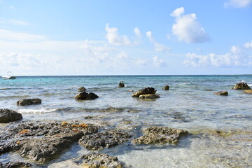 Serene rocky coastline with crystal-clear turquoise waters and a few small islands in the distance.