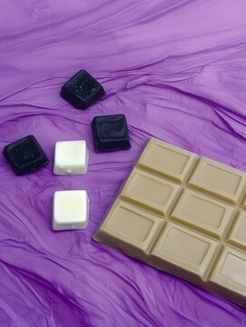 Black, white and milk chocolate board on purple fabric.