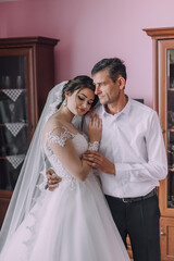 Naklejka premium A man and a woman are hugging each other in a room. The man is wearing a white shirt and the woman is wearing a wedding dress