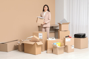 Young businesswoman packing things in office on moving day