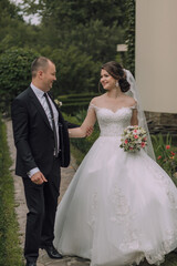 A bride and groom are walking down a path, the bride is wearing a white dress and the groom is wearing a suit