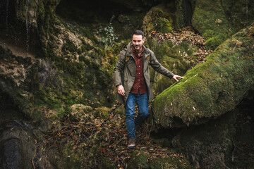 Naklejka premium Adult man hiker walk and explore scenic forest around rocks outdoor