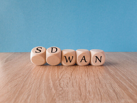Wooden cubes form the expression SD WAN. Symbol for Software defined Wide Area Networking. Beautiful blue background, wooden table.