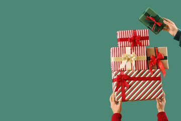 Female hands with stack of Christmas gifts on green background