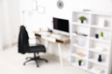 Blurred view of modern office with workplace and shelf unit