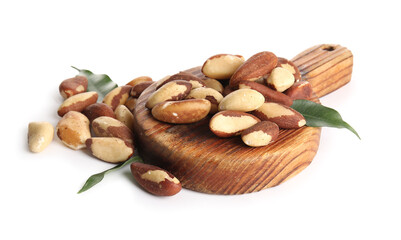 Wooden board with tasty Brazil nuts and leaves on white background