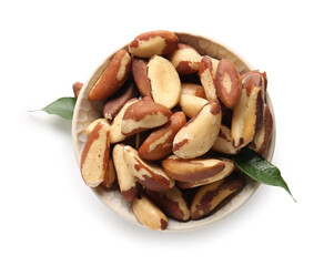 Bowl with tasty Brazil nuts and leaves on white background
